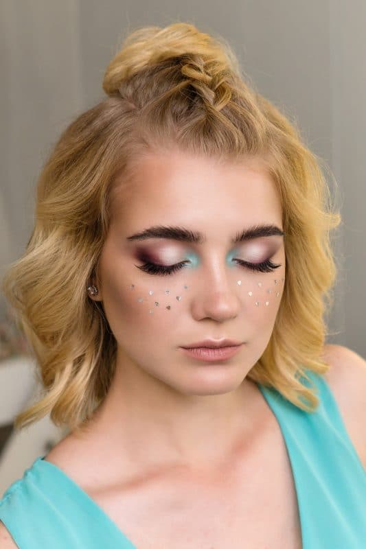 Mulher com maquiagem festiva e cabelo loiro preso em coque