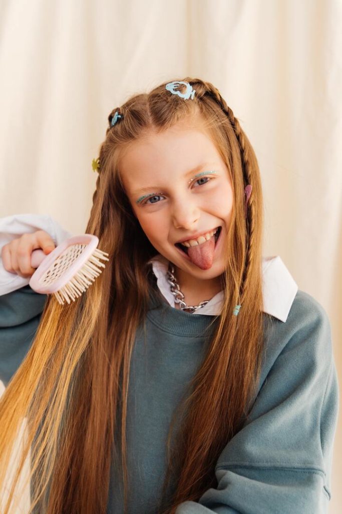 garota ruiva penteando os cabelos mostrando a lingua