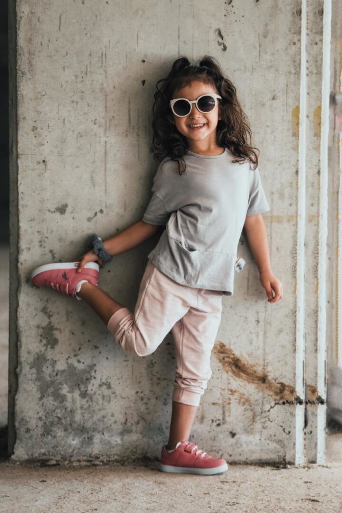 garota sorridente encostada na parede segurando os pés