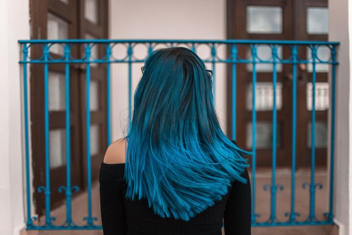  mulher de cabelos azuis em frente a cerca de metal
