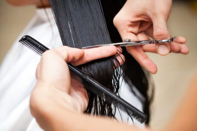 Mãos de um profissional cortando um cabelo