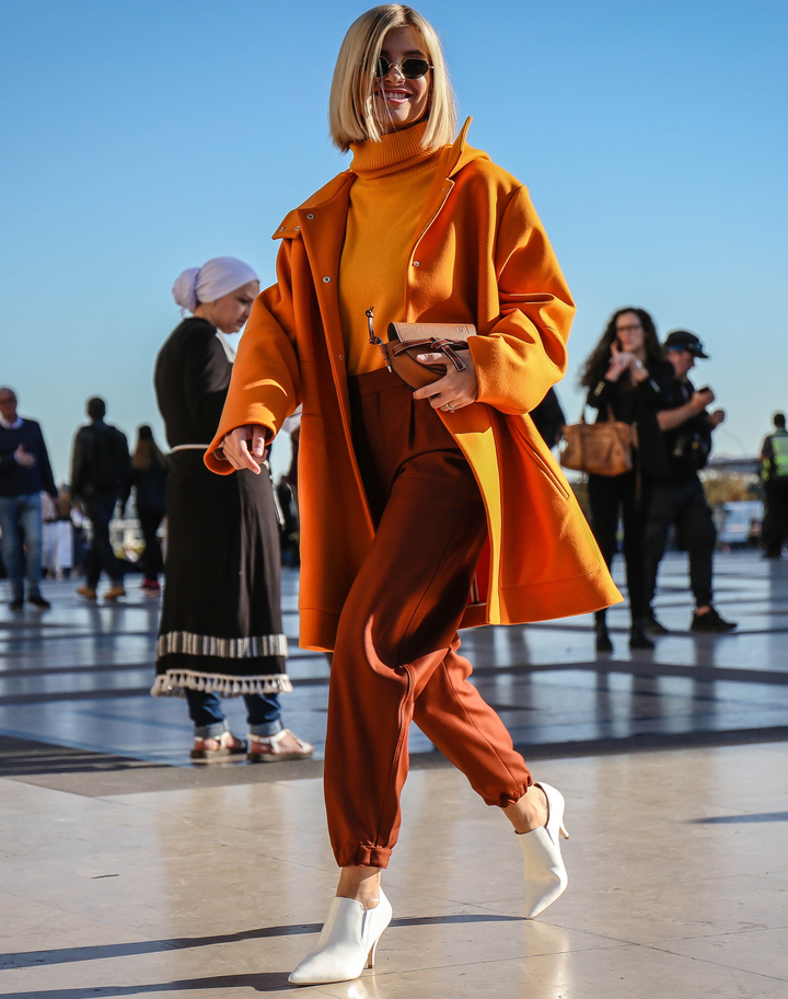 mulher branca usando look marrom e laranja