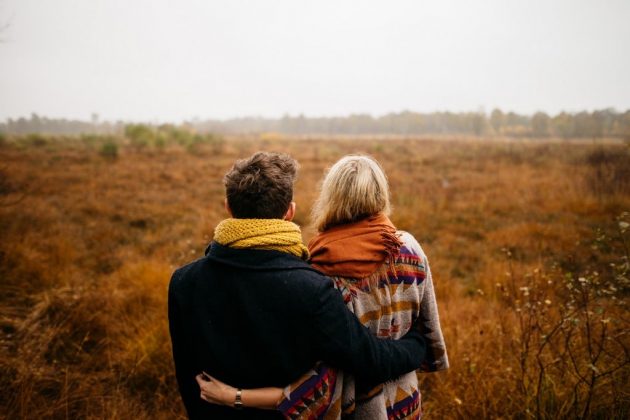 Casal virados de costas, abraçados enquanto observam uma paisagem da natureza