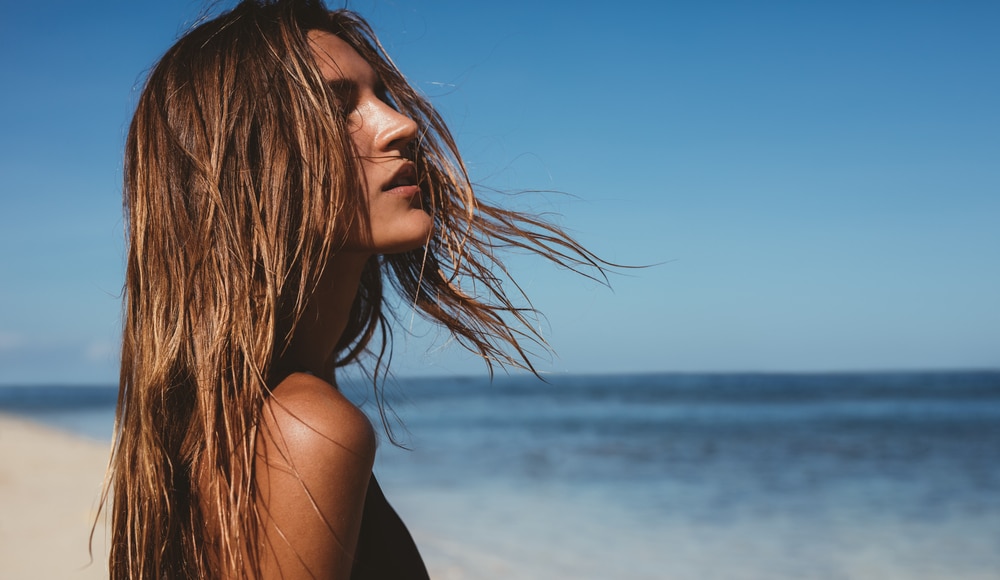  Mulher loira na praia, com água do mar no cabelo