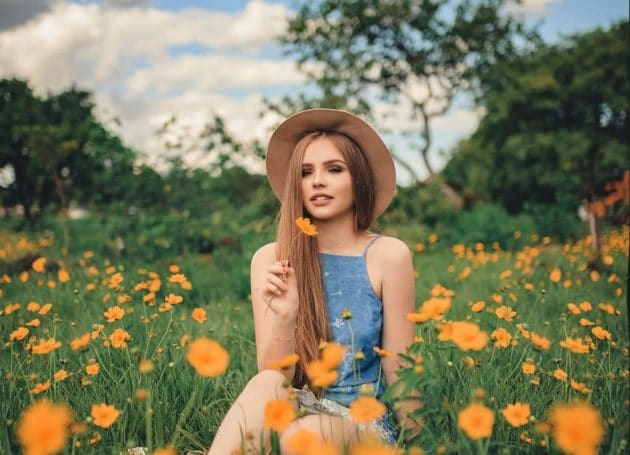 Modelo no jardim de flores com chapéu mostra todo seu charme com o cabelo liso grande