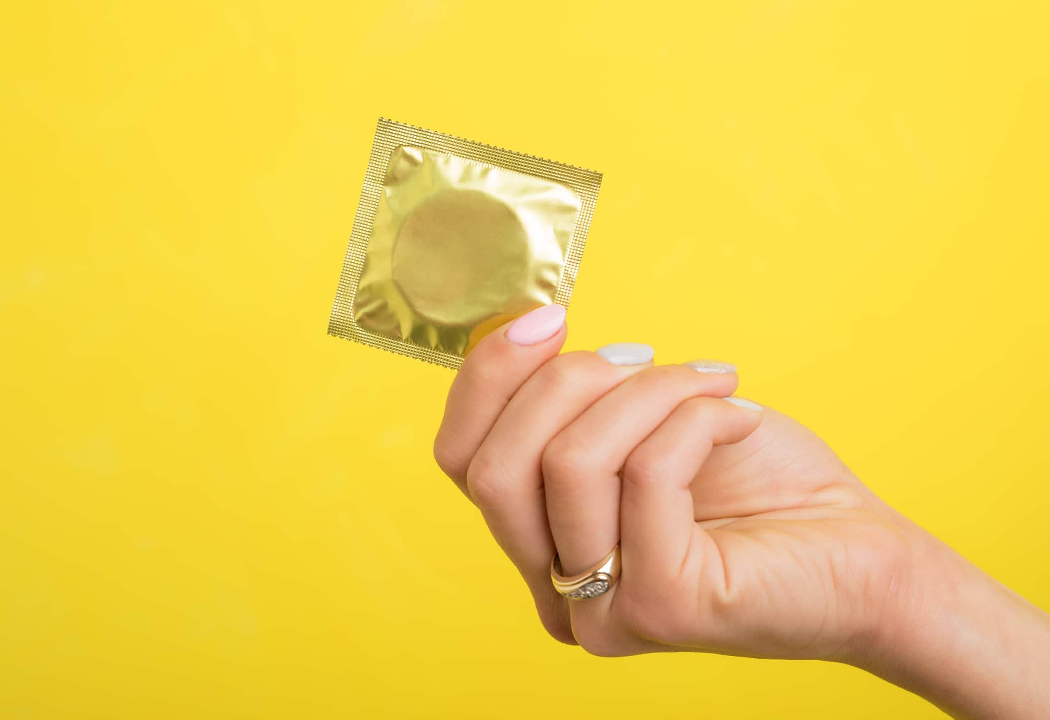  Mão feminina segurando um preservativo