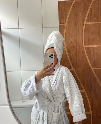  mulher que acabou de sair do banho, com toalha enrolada no cabelo, tirando foto no espelho