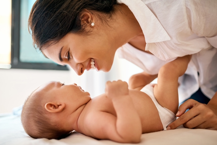 mãe sorrindo junto ao seu filho deitados na cama