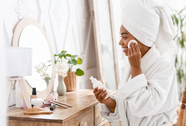 Mulher negra limpando o rosto com o produto adequado para seu tipo de pele