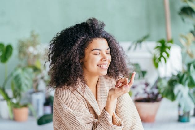 mulher de pele negra passando creme de vitamina E para o rosto