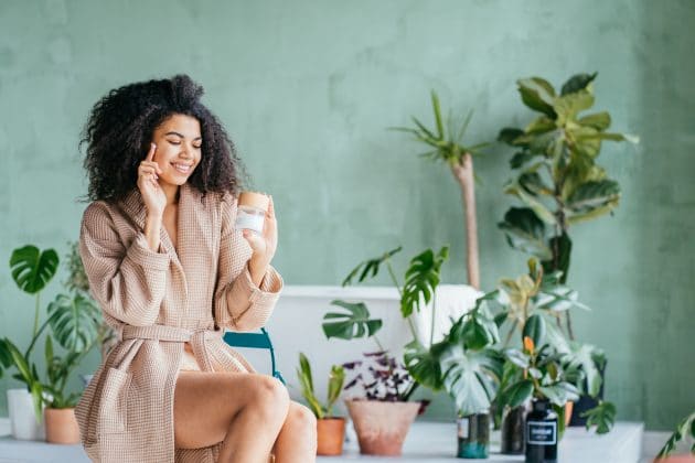 Mulher negra passando vitamina E no rosto