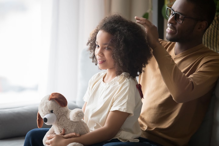  Homem negro desembaraçando o cabelo infantil da filha negra de cabelo cacheado