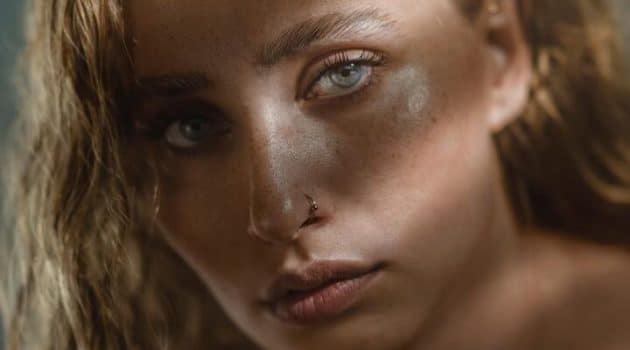 Mulher branca, de cabelo ondulado loiro e longo, maquiagem leve com a sobrancelha estilizada no efeito brow lamination