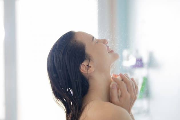 Mulher de cabelo liso, no chuveiro, lavando o cabelo com shampoo