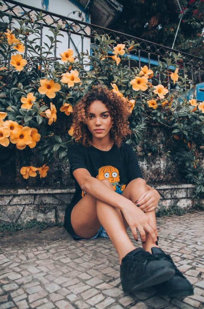 mulher com o cabelo crespo morena iluminado sentada em um jardim