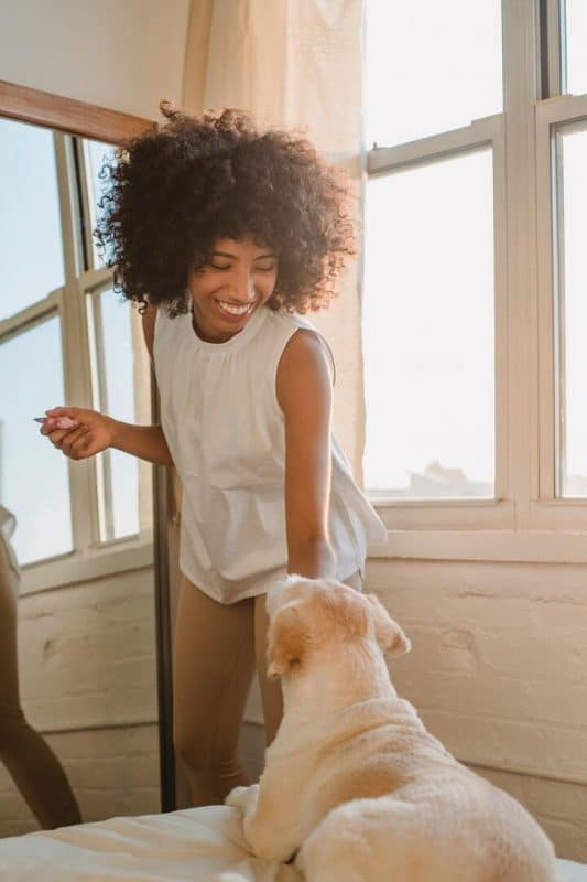 mulher com o cabelo crespo brincando com o cachorro