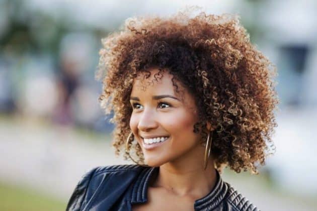 mulher de cabelo crespo com luzes sorrindo