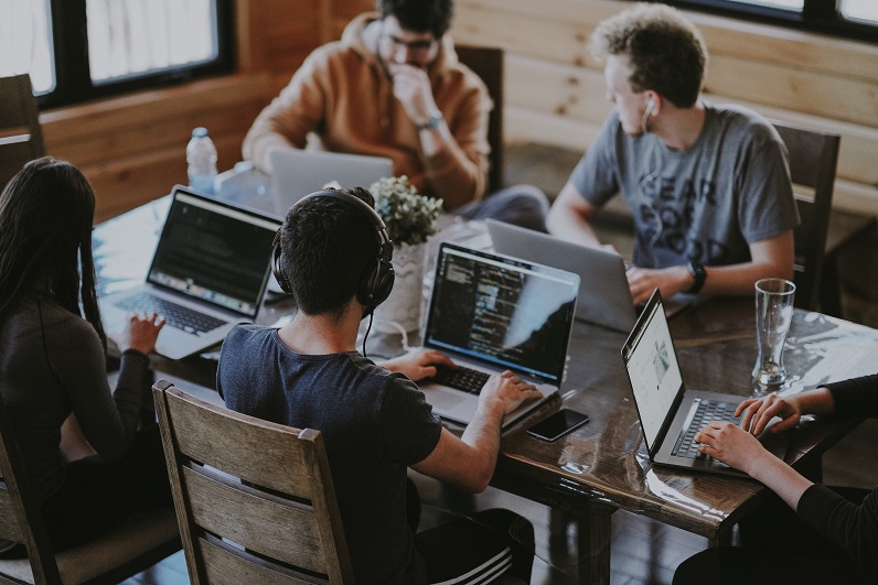  Grupo de jovens trabalhando em uma mesa, cada um com seu notebook