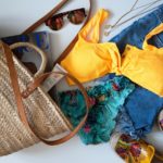 A imagem ilustra vários itens, acessórios e looks de verão, como: bolsa de praia, óculos de sol, biquini e short jeans