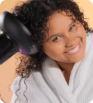 mulher negra usando difusor no cabelo cacheado