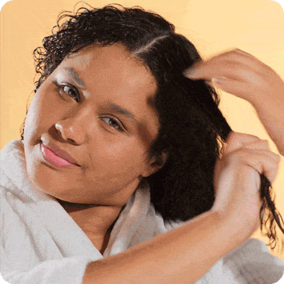 foto de uma mulher negra segurando uma mexa de seus cabelos cacheados
