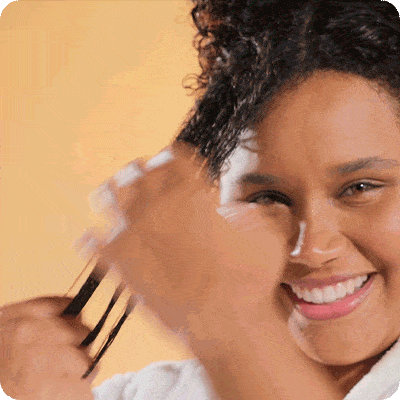 mulher negra sorrindo com os cabelos cacheados