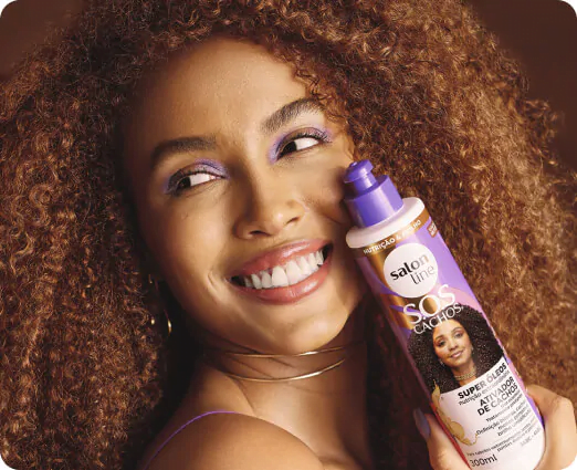 mulher negra de cabelos castanhos segurando um produto da Salon Line