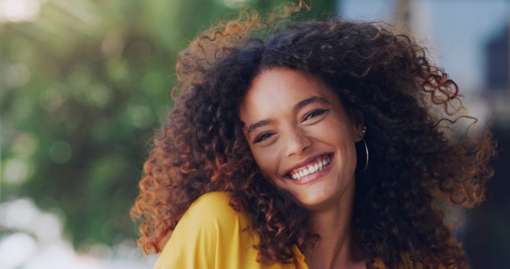 mulher de cabelo cacheado sorrindo